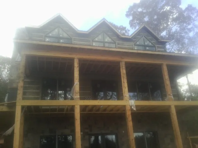 Dormers and porch framing on a large log home under construction — Roof Coating work by our crew in Rutland
